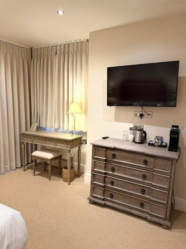 a hotel room with a desk and a flat screen tv at The Sunningdale in Bamburgh