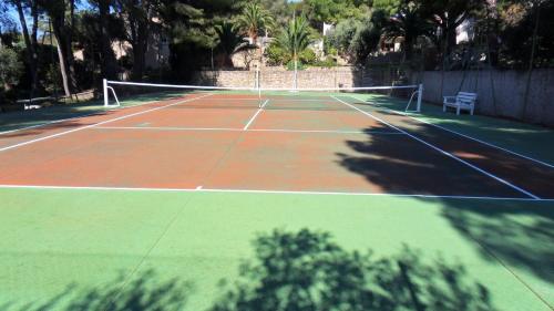 een tennisbaan met een net en een bankje erop bij Villa Serena in La Ciotat