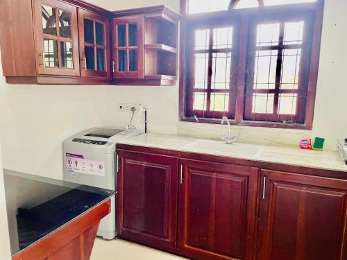 cocina con armarios de madera, fregadero y fogones en Buono Villa, en Negombo