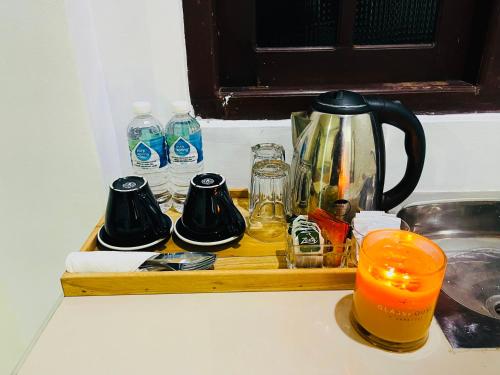 Una bandeja de madera con una cafetera y vasos sobre un mostrador. en Buono Villa, en Negombo