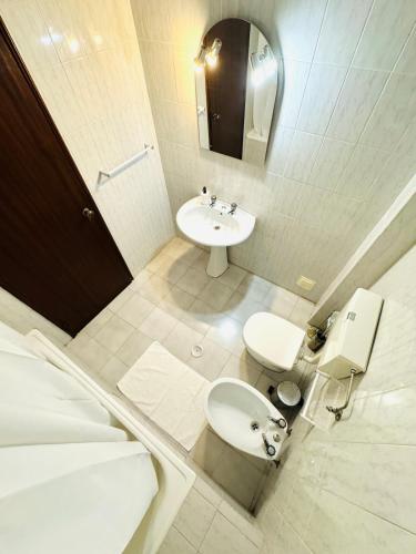 a white bathroom with a sink and a toilet at Apartamento gourmet com quintal in Albufeira