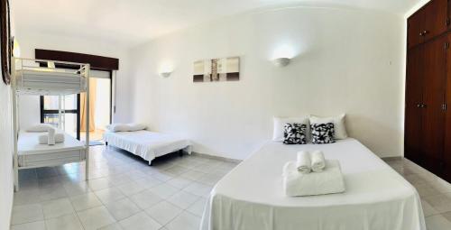 a white bedroom with a large bed and a couch at Apartamento gourmet com quintal in Albufeira