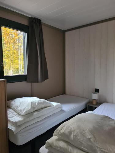 two beds in a room with a window at Chalet Lac du Der Giffaumont-Champaubert in Giffaumont-Champaubert