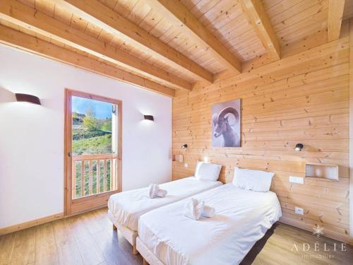 2 Betten in einem Zimmer mit Holzwänden und einem Fenster in der Unterkunft Chalet moderne, jacuzzi, sauna, 12 pers, proche pistes - FR-1-398-636 in Montvalezan