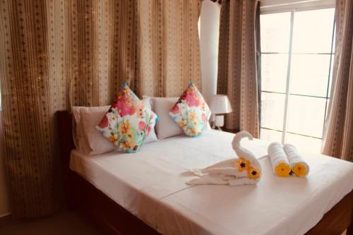 a bed with two stuffed animals on it with a window at H & M Bayview Apartment Seychelles in Beau Vallon