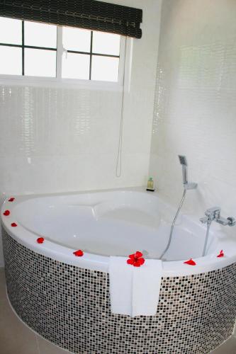 a white bath tub with a red bow on it at H & M Bayview Apartment Seychelles in Beau Vallon