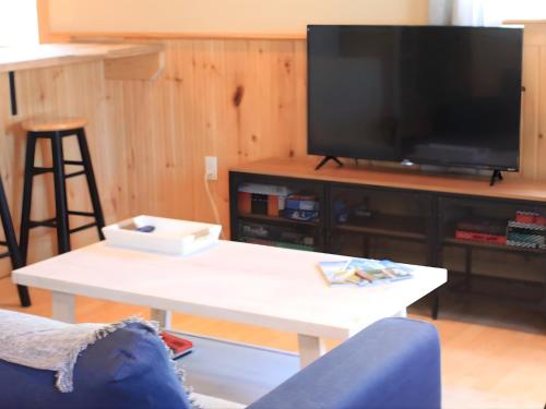 Il comprend un salon doté d'une télévision et d'une table basse blanche. dans l'établissement The Nook - Sherbrooke Cottages, à Summerside