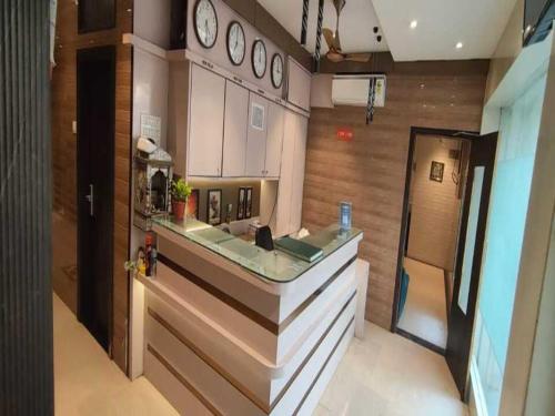 孟买Hotel Abrol Suites的厨房里有带水槽的台面，墙上挂着钟表。