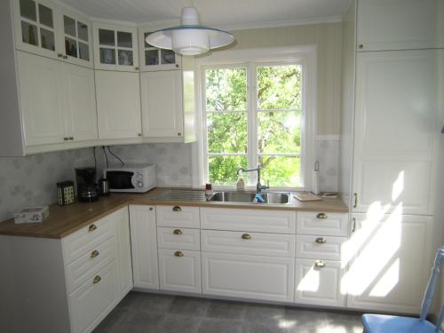a kitchen with white cabinets and a sink and a window at Bara Vara Garden in Tösse