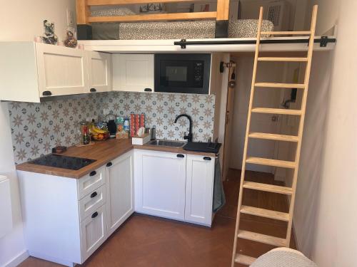 une cuisine avec des armoires blanches et une échelle dans l'établissement The cozy corner of Amelie, à Nice