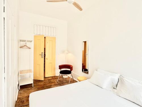 a white bedroom with a bed and a chair at Friendly Hills Bairro Alto in Lisbon