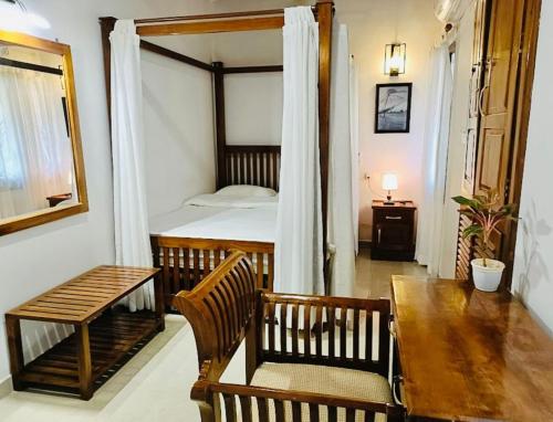 - une chambre avec un lit, une table et un banc dans l'établissement Boho Heritage in Kochi, à Cochin