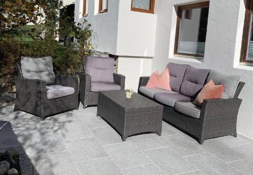 three wicker chairs and a table on a patio at Yvonne Mayer in Scuol