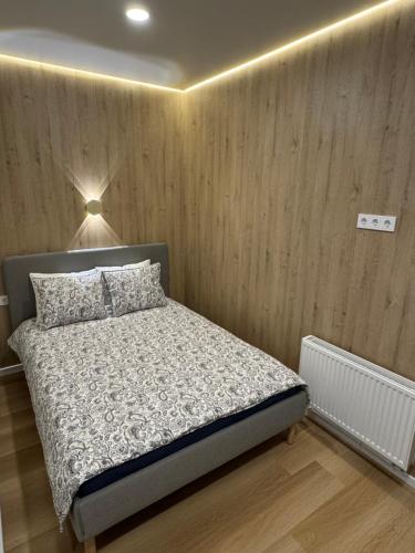 a bedroom with a bed and a wooden wall at 15 New Airport Apartment in Vilnius