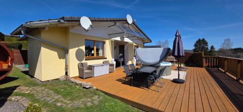 ein Haus mit einer Terrasse mit einem Tisch und Stühlen in der Unterkunft Ferienhaus Sonnenhuesli mit Sauna und Whirlpool auch Hunde sind herzlich willkommen in Lenzkirch