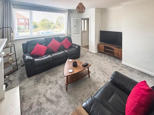a living room with a black leather couch and a table at The Miners House in Deal