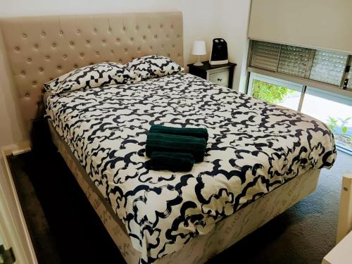 ein Schlafzimmer mit einem Bett mit einer schwarz-weißen Bettdecke in der Unterkunft Cozy and Comfy Homestay Rooms in Perth