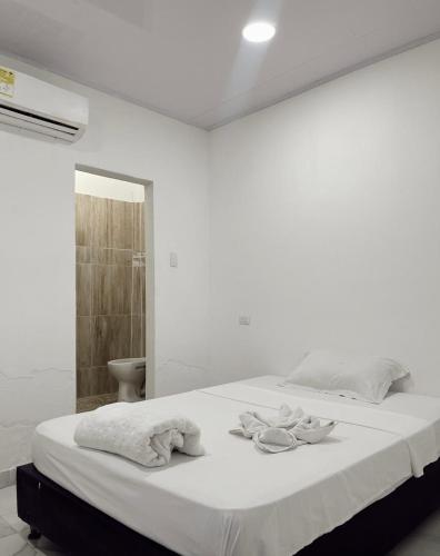 une chambre blanche avec un lit avec des serviettes dessus dans l'établissement El legado de las olas, à Carthagène des Indes