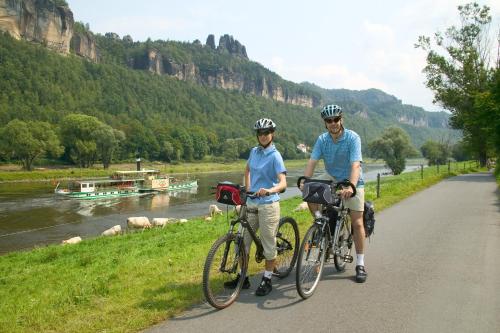 two people riding bikes on a road next to a river at aktiv Sporthotel Sächsische Schweiz in Pirna