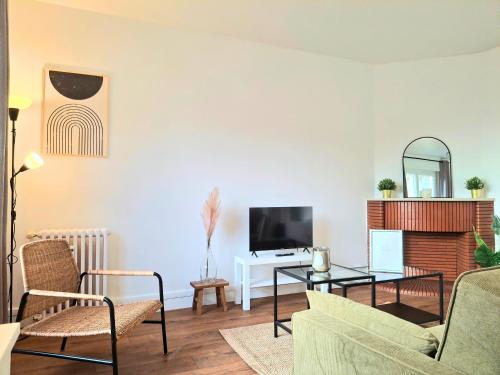 een woonkamer met een bank, een tafel en een tv bij Le Sweet Escape - Vue Sur La Cathédrale in Beauvais