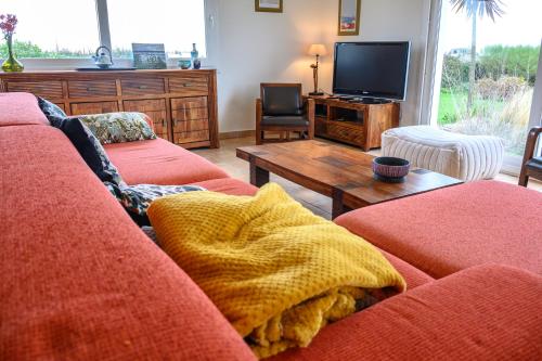 a living room with a red couch and a tv at Le repère de Saint Mathieu in Plougonvelin