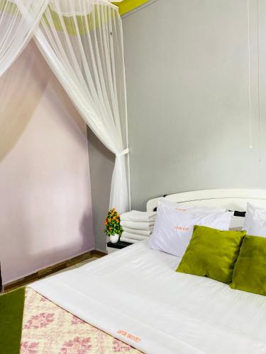 a bedroom with a bed with white sheets and green pillows at Jseason Faith-based retreat resort in Kagolomolo