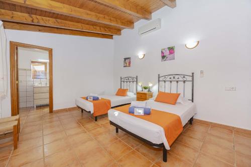 two beds in a room with white walls and wooden ceilings at Villa Marilen in Alcudia
