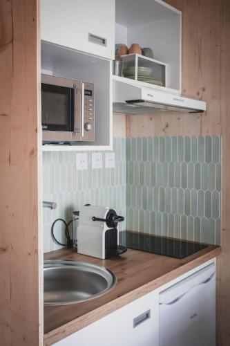a kitchen with a sink and a microwave at Le Studio du Hameau in Sales