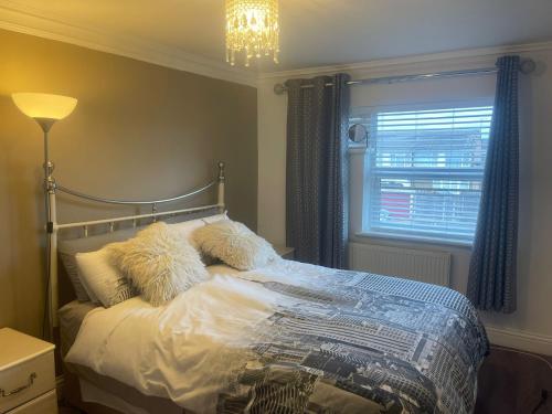 a bedroom with a bed with pillows and a window at Cassandra Homes in Nevendon