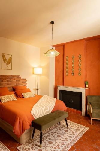 a bedroom with an orange bed and a fireplace at Cosy Cloître, appartement authentique centre Arles in Arles