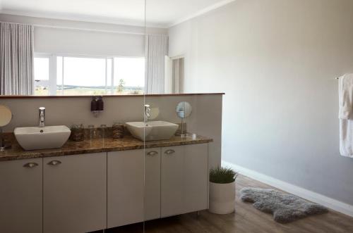 a bathroom with two sinks and a mirror at Brahman Hills - Gardens, Spa, Hotel & Villas - 5star in Nottingham Road