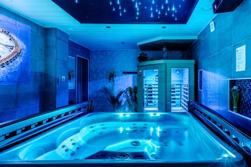 een jacuzzi in een kamer met blauwe verlichting bij Gites Spa Strasbourg - Villa Cerf - SPA Privé, Sauna, Borne d'arcade, Babyfoot in Ittenheim