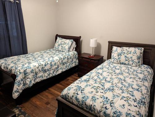 什里夫波特Charming, Quiet, South Shreveport Retreat King Bed的一间卧室，有两张床和一张带灯的桌子