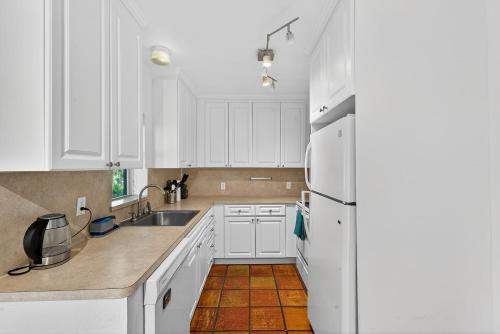 a white kitchen with white cabinets and a refrigerator at Sunny 2-Bedroom Miami Retreat with a Bright, Spacious Living Area & Relaxing Outdoor Seating in Fort Lauderdale