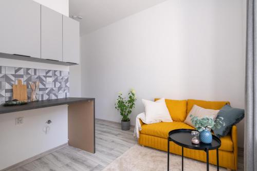 ein Wohnzimmer mit einem gelben Sofa und einem Tisch in der Unterkunft Nowoczesne Studio Mała Andrzeja, Kawalerka Inowrocław, Modern Studio, kamienica in Inowrocław