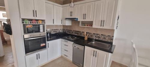 eine Küche mit weißen Schränken und schwarzen Arbeitsplatten in der Unterkunft Modern Front Seaview chalet El Sokhna in Ain Suchna