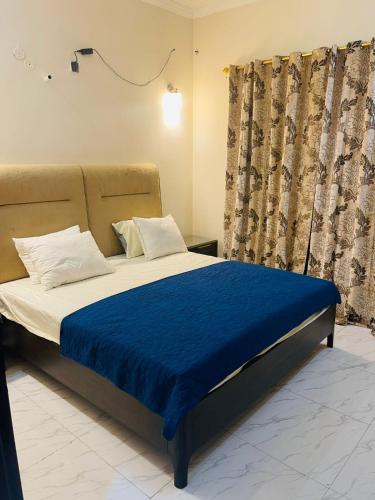 una camera da letto con un letto con una coperta blu di Luxury & Cozy Villa In the Heart of Bahria Town a Karachi