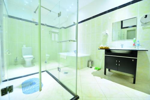 a bathroom with a shower and a sink and a toilet at The Manor Hotel in Kigali