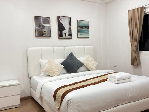a bedroom with a large white bed with four pictures on the wall at Pearl Homestay Hat Yai in Hat Yai