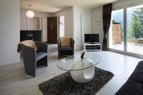 a living room with a glass table and chairs at Sirena in Scuol