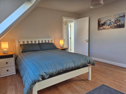 a bedroom with a bed with a blue comforter at Beautiful Spacious 4-Bedroom House in Louisburgh in Louisburgh
