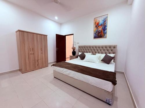 a bedroom with a large bed and a wooden cabinet at Blooming Residences by Gold Mark Property Consultants in Nugegoda