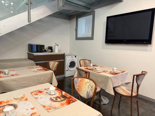 comedor con 2 mesas y TV de pantalla plana en Sweet Dreams Residence, en Brugine