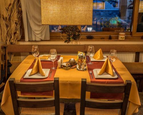 a dining table with a yellow table cloth and wine glasses at Family Hotel Eterno in Tsigov Chark