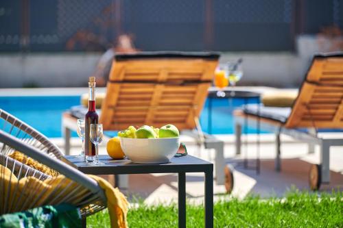 une table avec un bol de fruits et une bouteille de vin dans l'établissement Villa Dolcea Elegant Und Stilvoll Mit Pool, à Kaštel