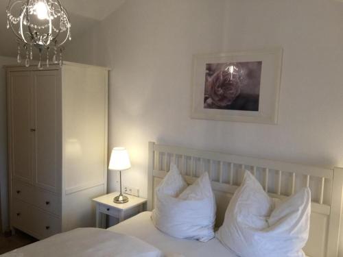 Schlafzimmer mit einem Bett mit weißen Kissen und einem Kronleuchter in der Unterkunft Das Haus mit Aussicht in Pirna