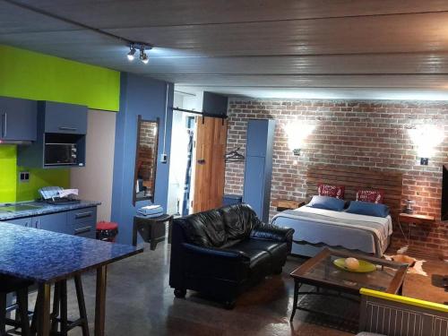 a room with a bed and a couch and a kitchen at The Regiment Self Catering Accommodation in Welgemoed