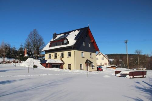 une grande maison avec un toit recouvert de neige dans l'établissement Fewo Erzgebirge, à Dorfchemnitz