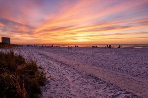 a sunset on a beach with footprints in the sand at Jamaica Royale Beach Villa in Siesta Key