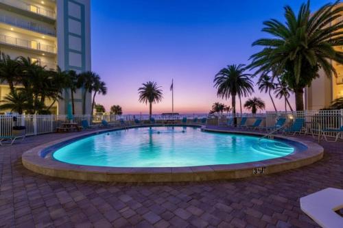 a swimming pool with palm trees and a building at Jamaica Royale Beach Villa in Siesta Key